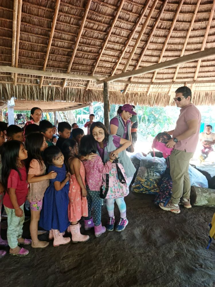 Voluntarios de la fundación entregan mochilas a niñas y niños en una comunidad amazónica