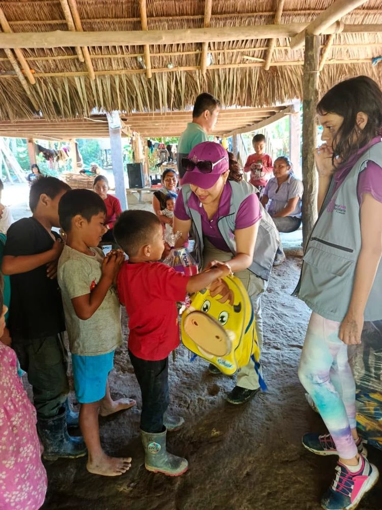 Voluntaria entrega una mochila a un niño